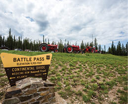 A sign is posted in a grassy field, indicating a battle pass. Two tractors are parked in the field, one red and one black. AI generated content
